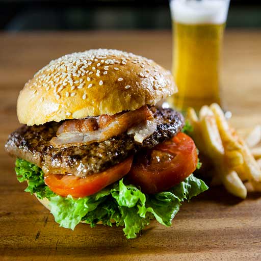 A BLT burger with a side of fries and a beer.